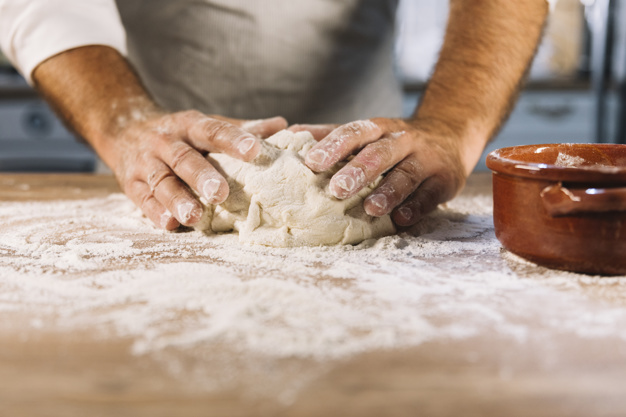 male-baker-kneading-dough-flour-wooden-table_23-2147926679